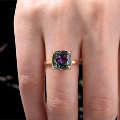 a woman's hand with a ring on it that has a purple diamond in the middle