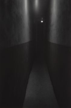 an empty hallway with black walls and white flooring is seen in this dark photo