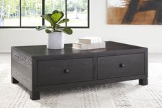 a black coffee table with two drawers and a potted plant sitting on top of it