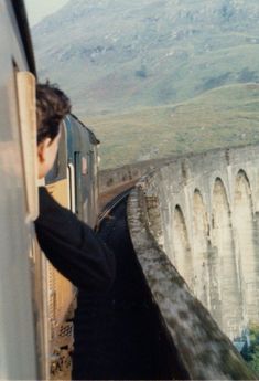 a man is looking out the window of a train as it passes over a bridge