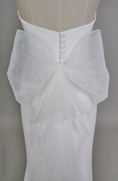 the back of a white wedding dress with sequins on it's sash