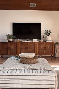 a large flat screen tv sitting on top of a wooden entertainment center in a living room