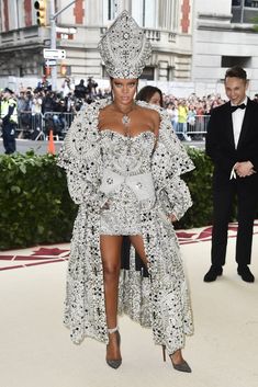 a woman in a silver dress and headdress at the mete fashion show