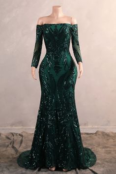 a green evening gown with long sleeves and sequins on the skirt is displayed in front of a mannequin