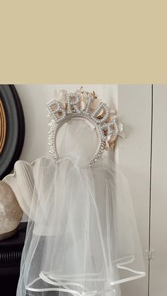 a tiara hanging on the wall in front of a mirror with veils draped over it