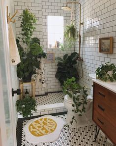 the bathroom is decorated in black and white tiles, with plants on the toilet seat