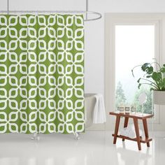 a bathroom with a green shower curtain and potted plant on the floor next to it