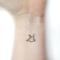 a small tattoo on the wrist of a woman with a bird flying above her head