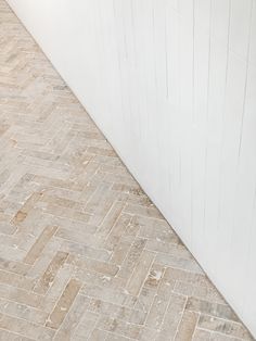 a white toilet sitting on top of a wooden floor next to a wall and tiled floor