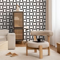 a living room scene with focus on the chair and wallpapered area that is decorated in black and white