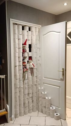 an open door with toilet paper on the floor and elf hats hanging from it's sides