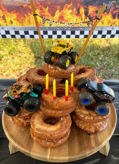 a wooden table topped with donuts covered in frosting and monster trucks sitting on top of each other