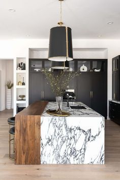 a large kitchen with marble counter tops and black cabinets, along with an island in the middle