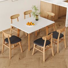 a white table with four chairs and a bowl of fruit on it in front of a kitchen counter