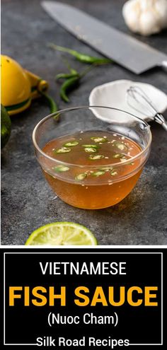 vietnamese fish sauce in a glass bowl with spoons and lemon slices on the side