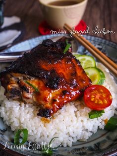 a plate topped with rice and meat next to chopsticks