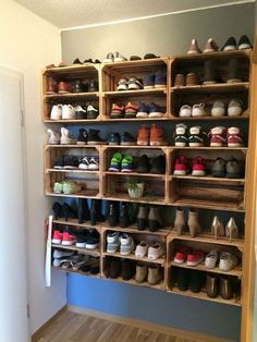 a wall filled with lots of pairs of shoes on wooden shelves next to a door