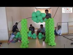 some people are sitting on the floor with green balloons