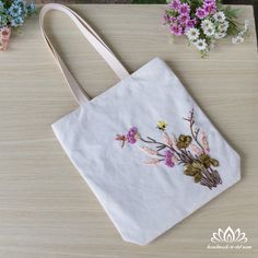 a white bag with embroidered flowers on it