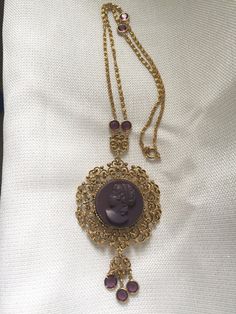 "Gorgeous 1950's statement watch pendant/necklace. Large gold plated medallion features a purple high relief carved profile cameo. Dangling down and attached to the chain are 7 round faux amethysts set in bezels. Lovely specialty chain has a large spring ring closure. The back has a Medana 17 Jewel mechanical wind watch, working well and winds easy. Necklace is 32\" long The pendant is 2 1/2\" in diameter My husband Alan & I had a brick & mortar store in Center City Philadelphia, on Jewe Vintage Cameo Medallion Necklace, Vintage Necklace With Coin Pendant, Vintage Long Necklace With Coin Pendant, Vintage Jewelry With Coin Pendant For Collectors, Vintage Collectible Jewelry With Coin Pendant, Vintage Antique Gold Long Necklace, Vintage Costume Jewelry Medallion Necklace, Collectible Vintage Jewelry With Coin Pendant, Vintage Yellow Gold Cameo Necklace