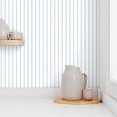 two white vases are sitting on a shelf in front of a striped wallpaper