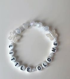 a white beaded bracelet with the words little love written on it and a butterfly charm