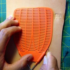 a person cutting an orange object with scissors