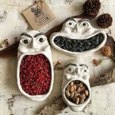 three ceramic bowls filled with fruit and nuts in the shape of people's faces