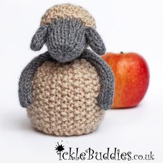 a crocheted stuffed animal sitting on top of an apple next to it's head