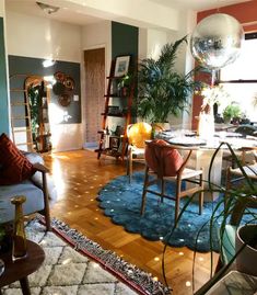 a living room filled with furniture and lots of plants on top of a hard wood floor