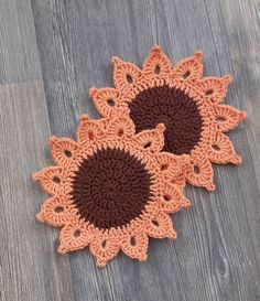 three crocheted doilys on a wood floor, one is orange and the other is brown