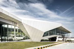 a white car is parked in front of a large building with glass windows and an awning