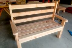 a wooden bench sitting on top of a floor next to a pile of wood planks