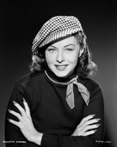 an old black and white photo of a woman wearing a hat with her arms crossed