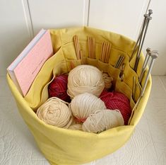 a yellow basket filled with yarn and knitting needles