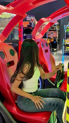 a woman is sitting in a car at an amusement park and has her hand on the steering wheel