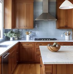 a large kitchen with wooden cabinets and marble counter tops, along with an island in the middle