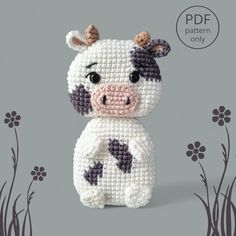 a small stuffed cow sitting on top of a gray surface with flowers in the background