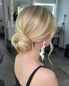 a woman with blonde hair in a black dress is looking at the camera and has her back to the camera