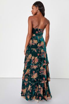 a woman wearing a green floral print dress with an open back and ruffled skirt