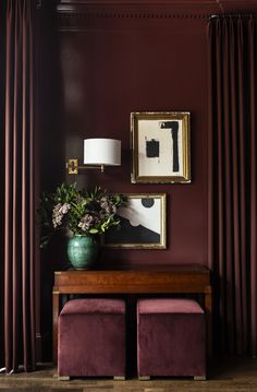 a living room with red walls and purple velvet stools next to a wooden table