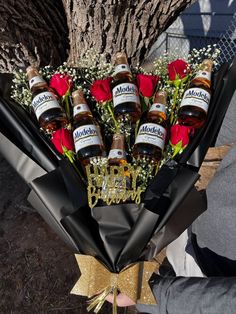 a bouquet of roses and bottles of alcohol in front of a tree with someone holding it