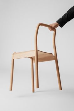 a wooden chair being held up by someone's hand