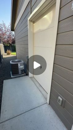 an air conditioner sitting on the side of a house next to a garage door