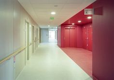 an empty hallway with red lockers on the walls and white carpeted flooring