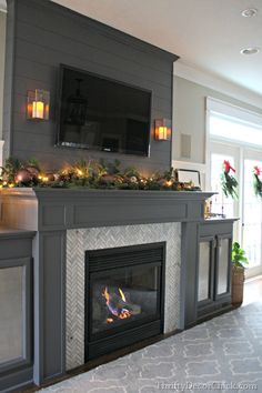 a living room with a fire place and christmas decorations on the mantel above it