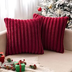 two red pillows sitting on top of a couch next to a christmas tree