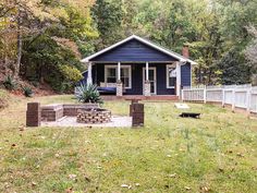 a small blue house with a fire pit in the front yard and fence around it