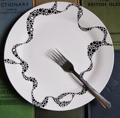 a white plate with black designs on it and a silver fork resting on the plate