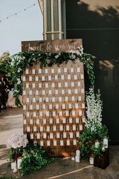 a wooden sign with greenery and candles on it